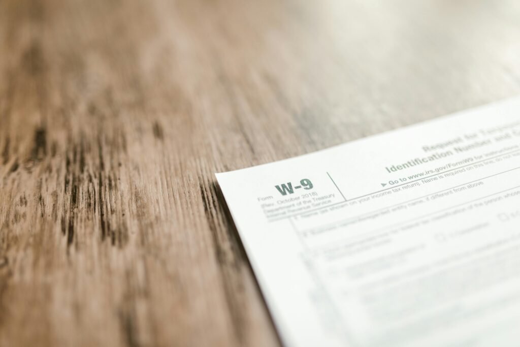 A close-up of a W-9 tax form placed on a wooden desk, emphasizing paperwork and finance.